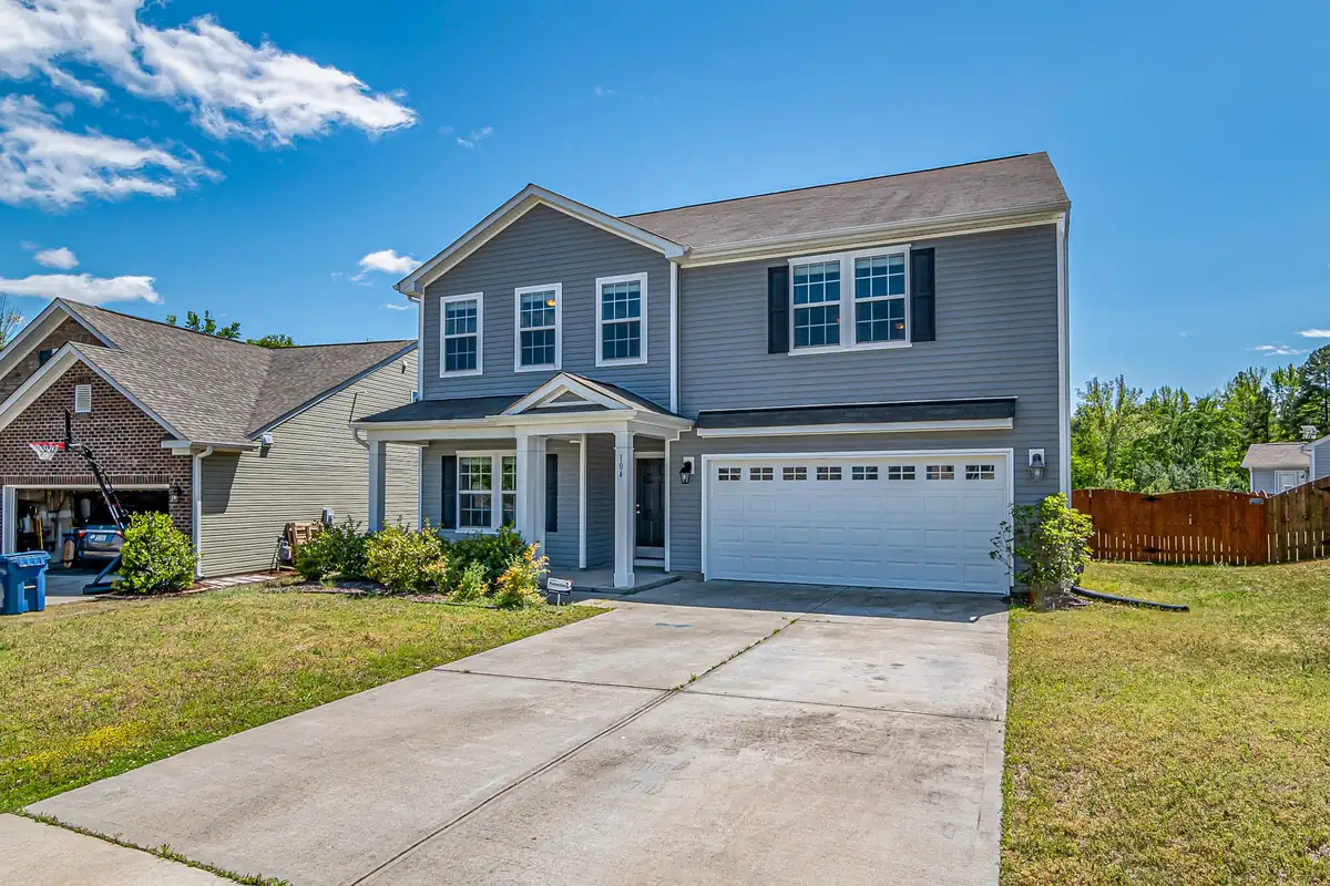 Two-story house with a broom-finished concrete driveway leading to a two-car garage, saw-cut control joints visible